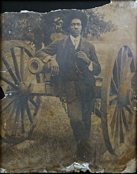 African American man leaning on Civil War 12 lb. Napoleon cannon